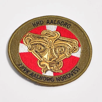 Rund broderet patch med tekst og detaljeret gyldent motiv